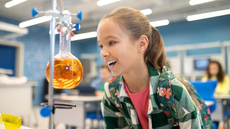 ["Girl with delight looking at flask in chemistry class"]