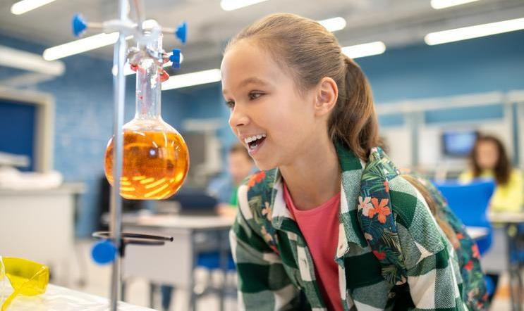 ["Girl with delight looking at flask in chemistry class"]