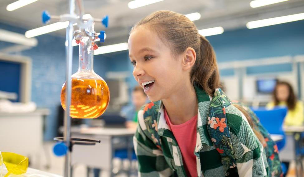 ["Girl with delight looking at flask in chemistry class"]