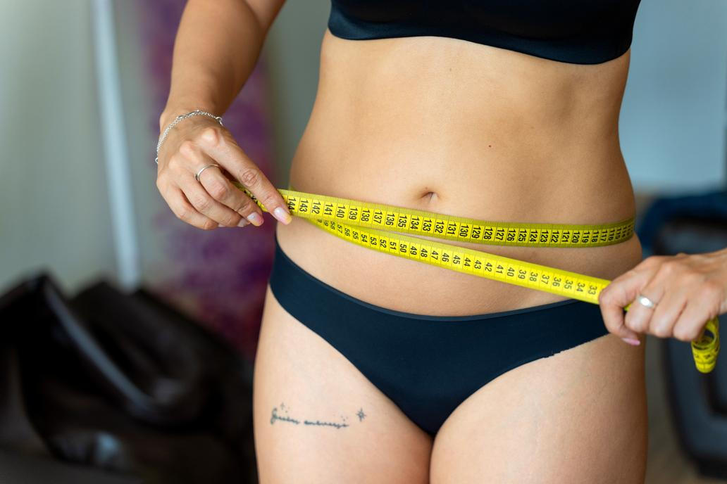 Woman,Measuring,Her,Waistline,With,A,Yellow,Measuring,Tape,,Tracking
