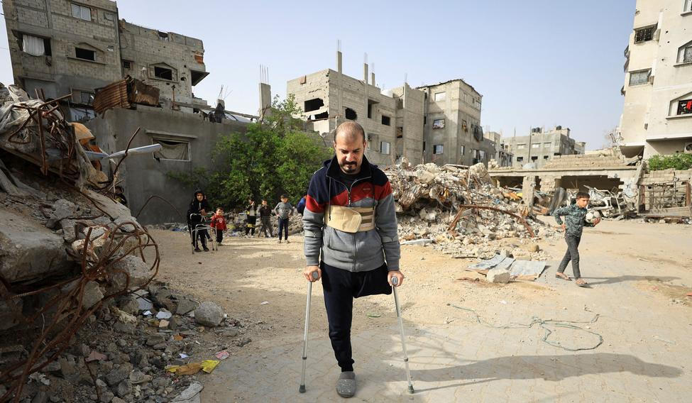Palestinian amputee Hazem Foura, who lost one leg, walks using crutches in a street in Gaza