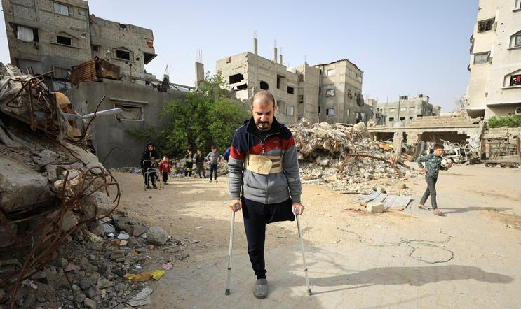 Palestinian amputee Hazem Foura, who lost one leg, walks using crutches in a street in Gaza