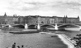 Předválečný výhled na Jiráskův most, na jehož úpatí stál až do roku 1945 rohový činžovní dům. Ten byl 14. února 1945 zničen zásahem americké bomby při leteckém bombardování Prahy. V roce 1963 bylo rozhodnuto o zástavbě proluky, ale až do 90. let nebyla realizována.