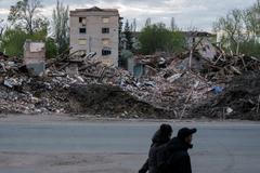 People walk next to destroyed buildings in the city of Sloviansk