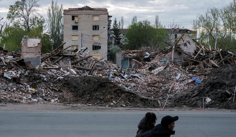 People walk next to destroyed buildings in the city of Sloviansk