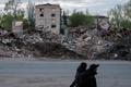 People walk next to destroyed buildings in the city of Sloviansk