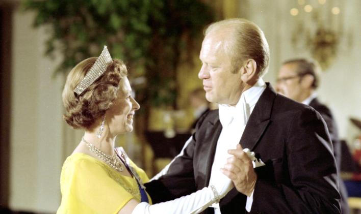 The queen, in a yellow dress, white gloves and tiara dancing with President Ford, in formal evening wear.
President Gerald R. Ford with Queen Elizabeth at a White House state dinner in 1976
