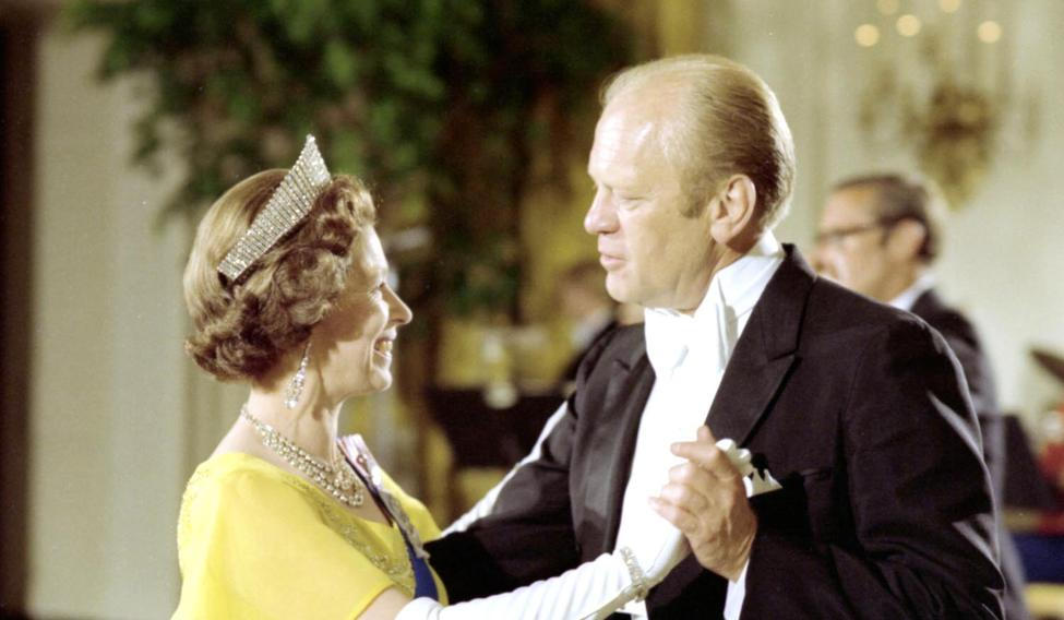 The queen, in a yellow dress, white gloves and tiara dancing with President Ford, in formal evening wear.
President Gerald R. Ford with Queen Elizabeth at a White House state dinner in 1976
