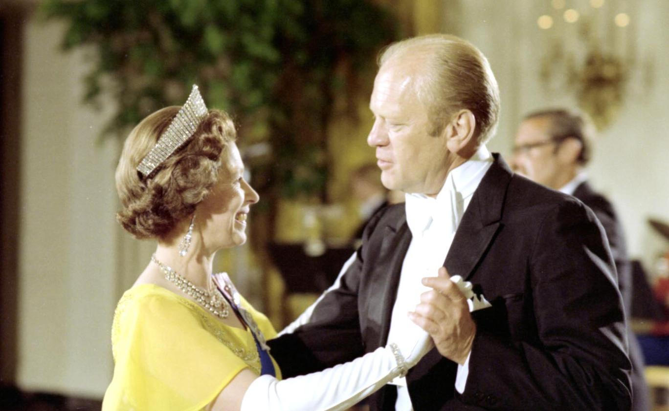 The queen, in a yellow dress, white gloves and tiara dancing with President Ford, in formal evening wear.
President Gerald R. Ford with Queen Elizabeth at a White House state dinner in 1976
