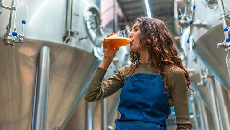 Woman,Wearing,An,Apron,Tasting,A,Glass,Of,Freshly,Brewed