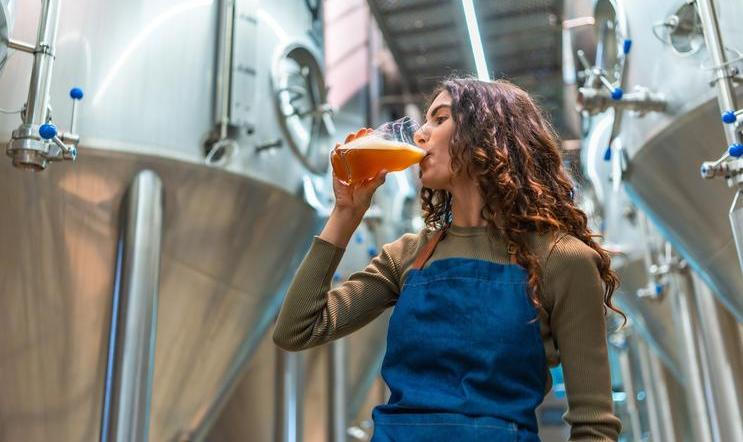 Woman,Wearing,An,Apron,Tasting,A,Glass,Of,Freshly,Brewed