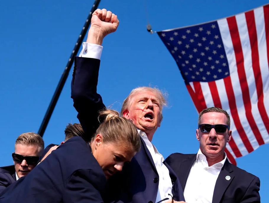 Donald Trump byl postřelen na předvolebním mítinku 13. 7. 2024 v Pensylvánii. Jeho gesto, než byl odveden z pódia, se stalo symbolem. Útočník byl zastřelen. Incident si vyžádal jednu oběť z publika a dva těžce zraněné.