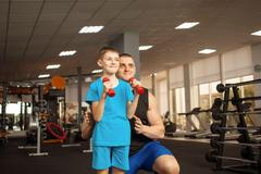 child performs an exercise with dumbbells with a trainer