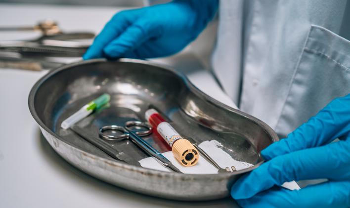 ["Nurse in rubber gloves holding a tray of surgical medical equipment"]