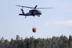 A helicopter carries water during efforts to extinguish a forest fire near Jozefow