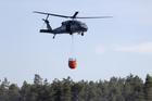 A helicopter carries water during efforts to extinguish a forest fire near Jozefow