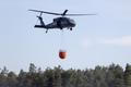 A helicopter carries water during efforts to extinguish a forest fire near Jozefow