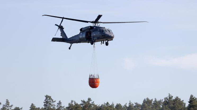 A helicopter carries water during efforts to extinguish a forest fire near Jozefow
