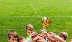 Kids soccer football - young children players celebrating with a trophy after match on soccer field