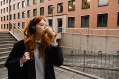 Young,Redhead,Woman,In,Wireless,Headphones,Drinking,Takeaway,Coffee,While
