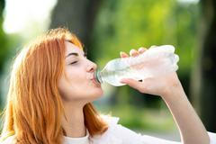 Young,Thirsty,Redhead,Woman,Drinking,Water,From,A,Bottle,In