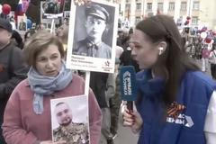 Žena ukazuje reportérce fotografie. Na jedné z nich je její dědeček, na druhé syn. 9. května 2026.
