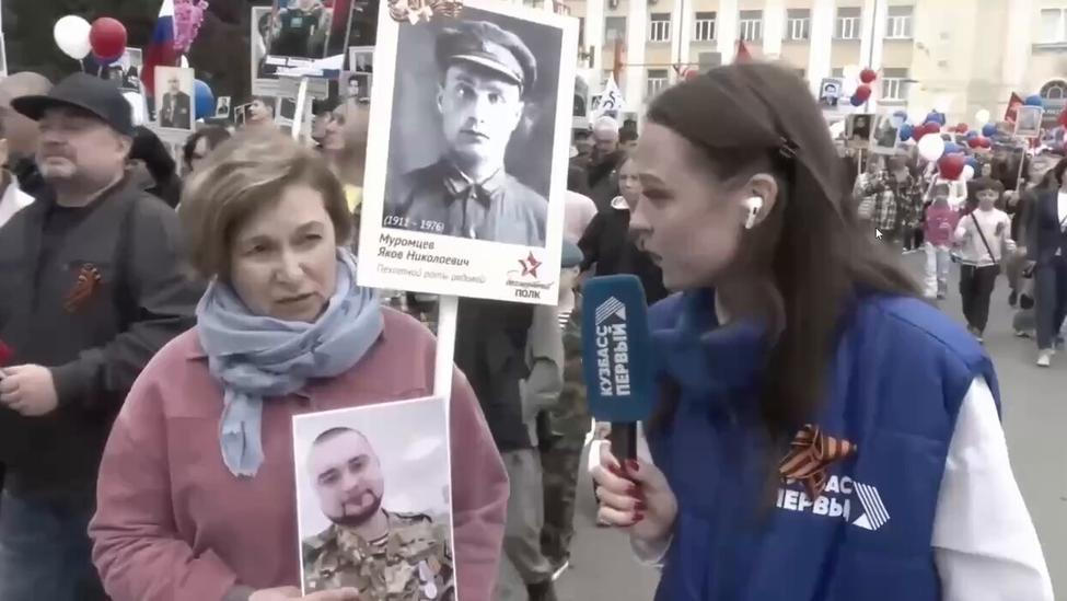 Žena ukazuje reportérce fotografie. Na jedné z nich je její dědeček, na druhé syn. 9. května 2026.