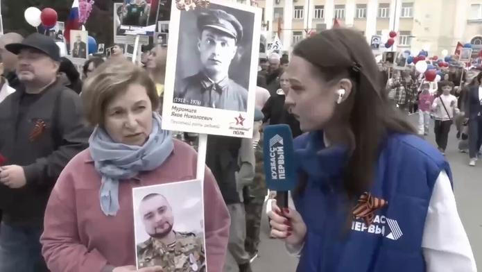 Žena ukazuje reportérce fotografie. Na jedné z nich je její dědeček, na druhé syn. 9. května 2026.