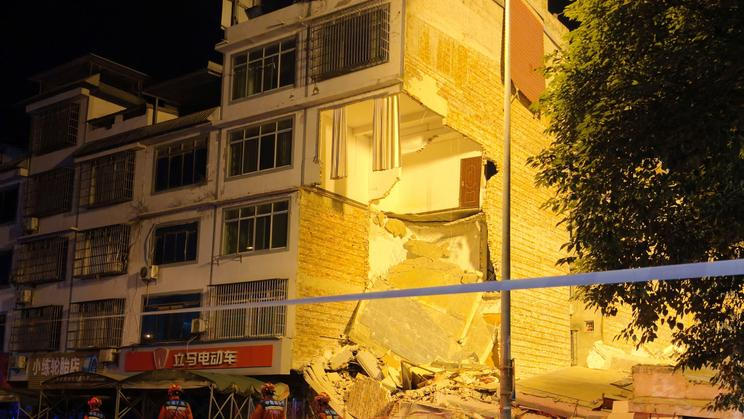 Rescue workers walk past a damaged building following an earthquake in Liuzhou