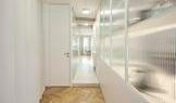 Bílý vestavěný nábytek pak nechává vyniknout struktury materiálů, zatímco závěsy přinášejí měkkost i funkci. „Závěs vnímáme jako plnohodnotný architektonický prvek. Umožňuje okamžitě změnit atmosféru i míru soukromí,“ doplňují autoři.