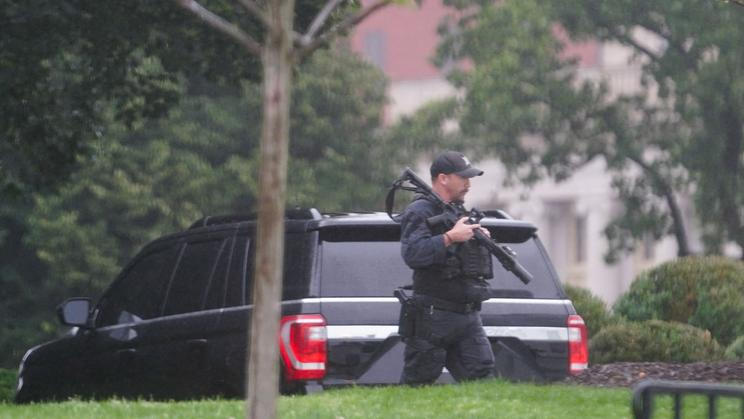A U.S. Secret Service agent walks holding his weapon after alleged gunshots were heard nearby, at the White House in Washington