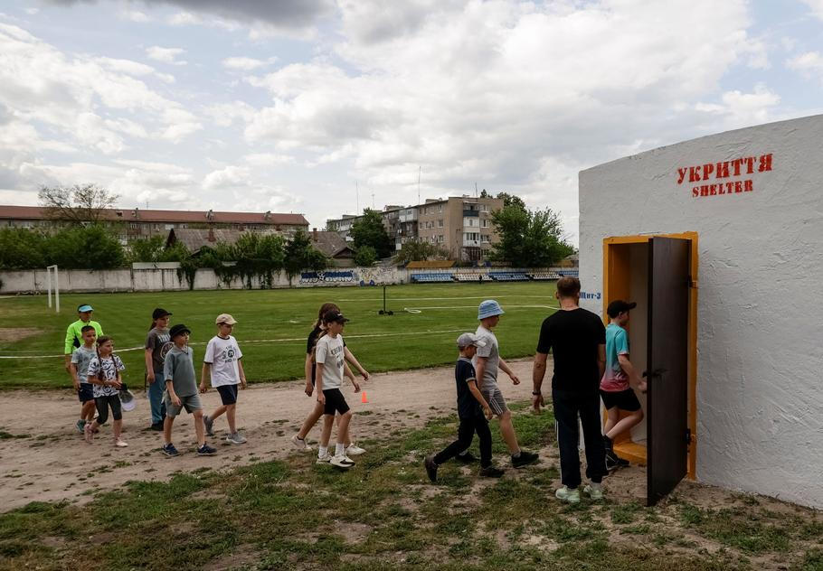 Schoolchildren go into an underground shelter near their school in the town of Balakliia