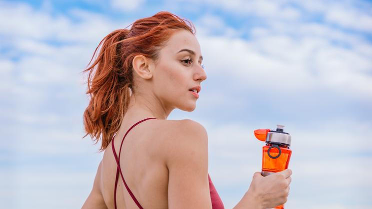 Smiling,Athletic,Woman,Holding,Water,Bottle,Outdoors,Under,Blue,Sky
