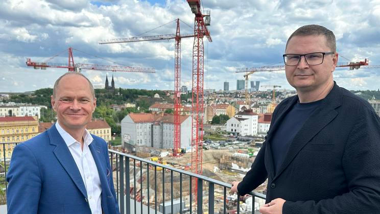Výkonný ředitel Sekyra Group Leoš Anderle (vpravo) a ředitel developmentu Sekyra Group Igor Klajmon (vlevo) ukazují z terasy střechy bytového domu stavbu výjimečné smíchovské čtvrti.