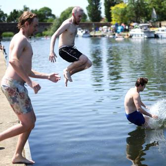 People jump into the River Great Ouse as temperatures climb over the bank holiday weekend during a heatwave, in Great Barford