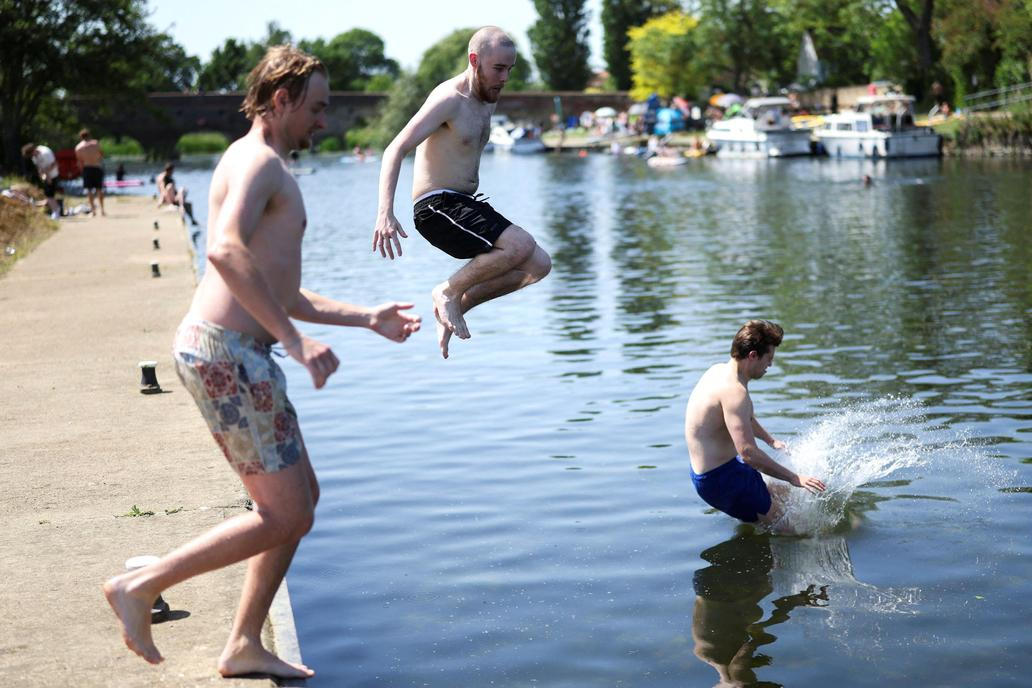 People jump into the River Great Ouse as temperatures climb over the bank holiday weekend during a heatwave, in Great Barford