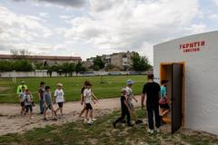 Schoolchildren go into an underground shelter near their school in the town of Balakliia