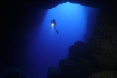 Scuba,Divers,Underwater,Exploring,Caves,Blue,Ocean,Scenery,With,Torch