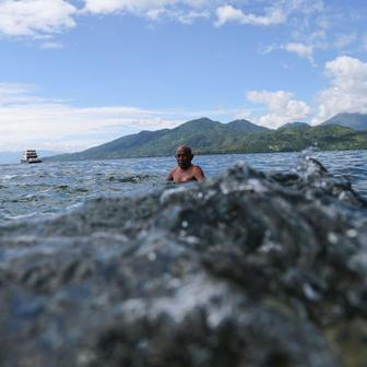 A man swims near Falajawa beach as the Meteorology, Climatology, and Geophysical agency issued a tsunami warning in Ternate