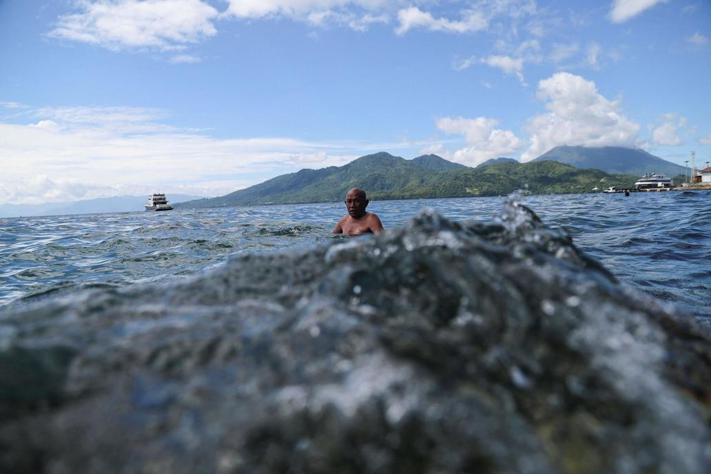 A man swims near Falajawa beach as the Meteorology, Climatology, and Geophysical agency issued a tsunami warning in Ternate