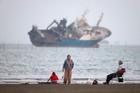 FILE PHOTO: People gather on a beach, as a vessel in the Strait of Hormuz is visible, near the beach of Bandar Abbas