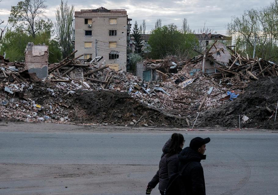 People walk next to destroyed buildings in the city of Sloviansk