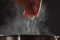 Man,Adding,Salt,To,Boiling,Water,In,Saucepan,With,Strong