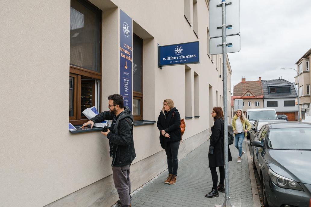 První chleby a croissanty začali prodávat z nenápadného okénka v brněnských Žabovřeskách, zpočátku jen odpoledne. Pak se stalo něco, co změnilo směr celého podnikání: před okénkem se začaly tvořit fronty. „Najednou jsme měli frontu na chleba. Byli jsme úplně nadšení,“ vzpomíná Ráček. 

