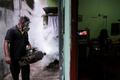 A resident watches television as a health worker from the Medical Officer of Health (MOH) department fumigates an area during a mosquito control programme in Colombo