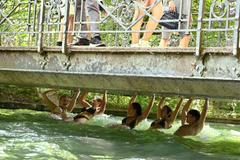 People swim along with the current of the Eisbach in the English Garden all the way to the nearest tram stop in Munich