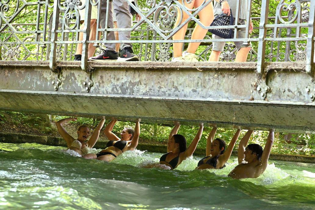 People swim along with the current of the Eisbach in the English Garden all the way to the nearest tram stop in Munich