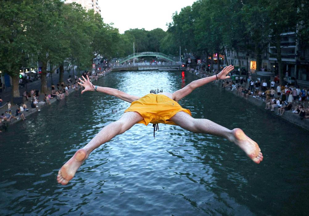 A man dives into the water in the Canal Saint-Martin in Paris
