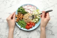 Woman,Eating,Different,Healthy,Vegetarian,Food,At,White,Marble,Table,