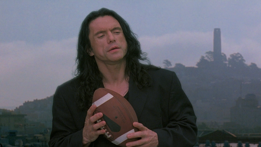 Tommy Wiseau jako představitel hlavního hrdiny Johnnyho ve filmu The Room (2003). Snímek, který se proslavil jako jeden z nejhorších filmů všech dob, Wisseau také sám režíroval a napsal k němu scénář.